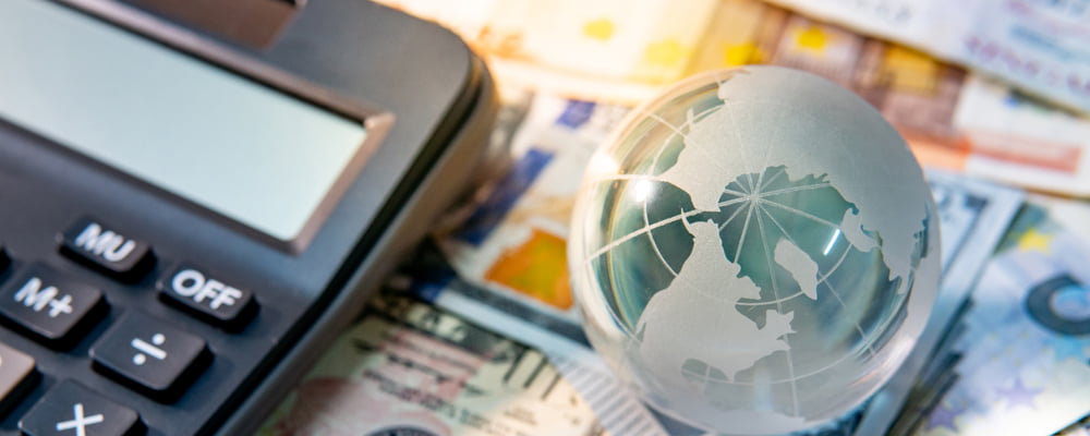 Image of a calculator, international currency and a small globe